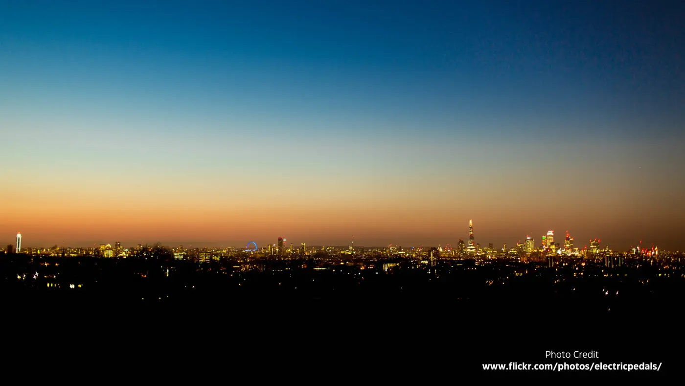 The city at night from the reservoir: a thin band of orange on the horizon above thousands of lights.