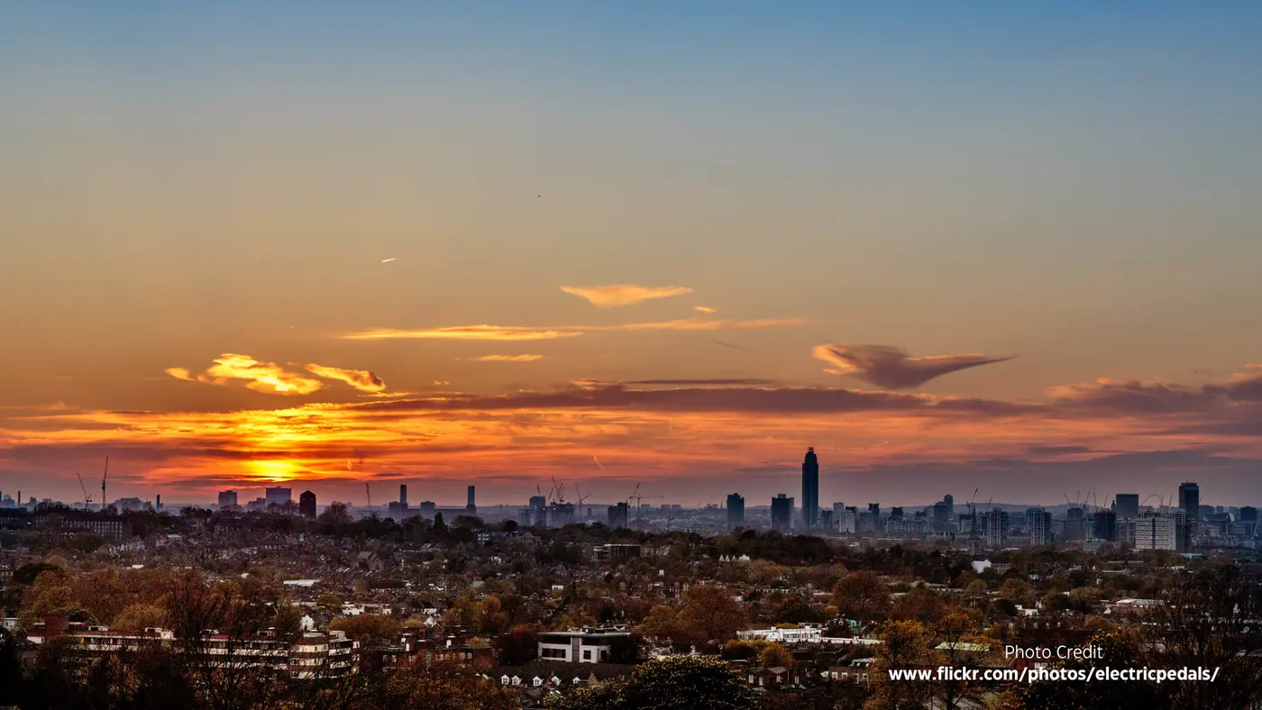 An orange and grey sunset over the whole of south London seen from the reservoir, with tower blocks catching the last light.